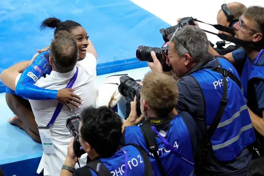 The United States's Simone Biles celebrates with a coach after winning the gold medal during the women's all-round final at the Artistic Gymnastics World Championships in Antwerp, Belgium, October 6. Biles was named the AP Female Athlete of the Year for a third time on December 22, after winning national and world all-around titles in her return to gymnastics following a two-year break after the Tokyo Olympics. [Virginia Mayo/AP Photo]
