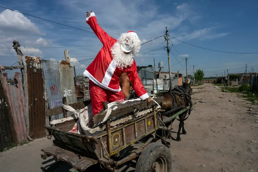 Tito Perez, dressed as Santa Claus, waves to children while standing on the back of a horse cart, at a pre-Christmas celebration organized by "Los Chicos de la Via" soup kitchen, in Buenos Aires, Argentina, December 23. [Rodrigo Abd/AP Photo]