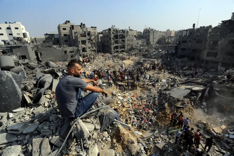 A man sits on rubble as others search among the debris of buildings targeted by Israeli air strikes in Jabaliya refugee camp, the northern Gaza Strip, on November 1. [Abed Khaled/AP Photo]