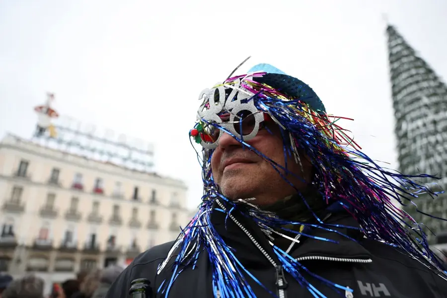 A man wears 2024 fancy party glasses and wig during a rehearsal for New Year's Eve celebrations at the landmark Puerta del Sol Square, in Madrid, Spain [Isabel Infantes/Reuters]