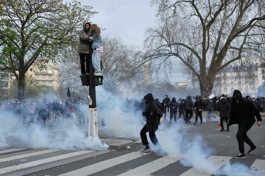 People stand on a traffic light amid clashes on the 10th day of nationwide strikes and protests against the French government's pension reform in Paris, France, on March 28. [Nacho Doce/Reuters]