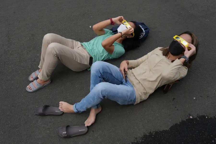 People lie on the ground as they use protective eyewear to watch a solar eclipse in Jakarta, Indonesia, April 20. A rare solar eclipse crossed over remote parts of Australia, Indonesia and East Timor. [Tatan Syuflana/AP Photo]