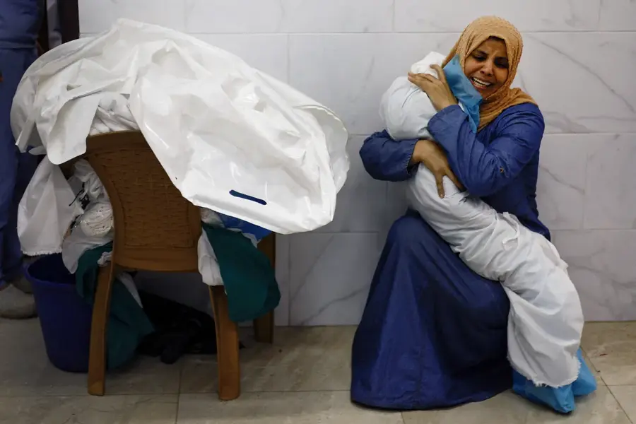 Palestinian woman Inas Abu Maamar embraces the body of her five-year-old niece Saly, who was killed in an Israeli attack, at Nasser hospital in Khan Younis on October 17, 2023. [Mohammed Salem/Reuters]