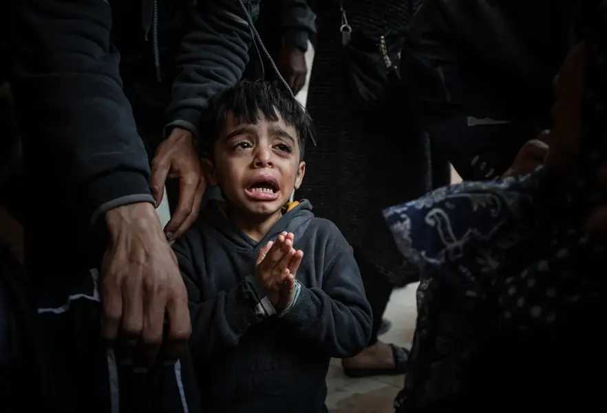 A Palestinian child cries as bodies of those killed in the attacks were brought to the morgue of Nasser hospital in Khan Younis. [Belal Khaled/Anadolu]