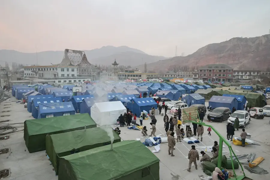 People are seen at a temporary shelter in the main square in Dahejia, in Jishishan County, Gansu province, on December 20, 2023. Survivors of China's deadliest earthquake in years huddled in aid tents after overnight temperatures plunged well below zero, with the death toll rising to 131. [Pedro Pardo/AFP]